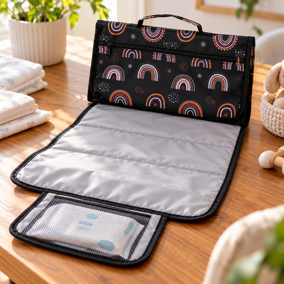 Close-up of the open foldable changing pad showing the padded wipeable surface, wipes pocket, zipper pocket and handle
