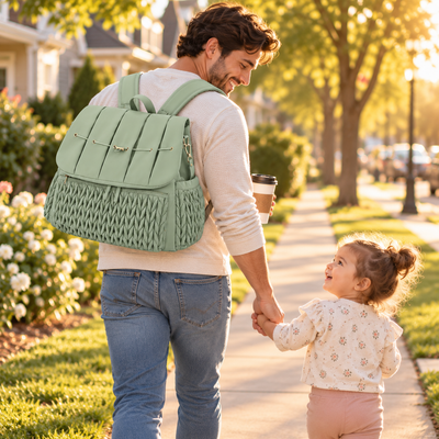 Father walking with his toddler wearing the sage green quilted diaper bag as a backpack