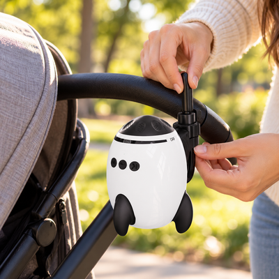 Close-up of hands clipping the stroller soother onto the stroller handlebar